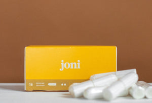 A yellow box of joni regular tampons with some loose digital tampons resting in front of the box